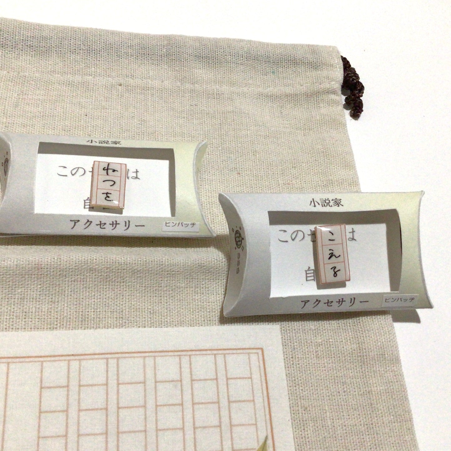 原稿用紙の巾着袋とピンバッジのセット